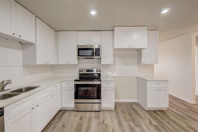 kitchen featuring light hardwood / wood-style flooring, stainless steel appliances, backsplash, sink, and white cabinets