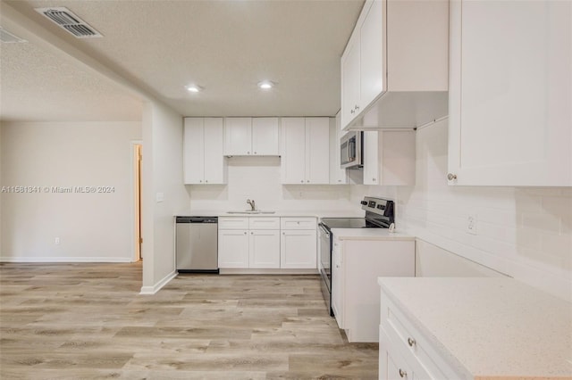 kitchen featuring appliances with stainless steel finishes, sink, white cabinets, and light wood-type flooring