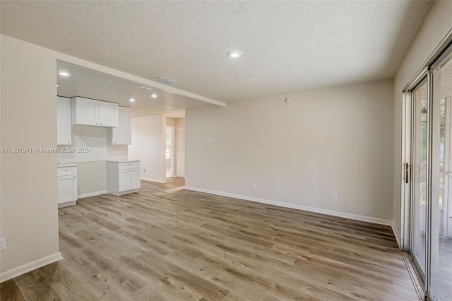 unfurnished living room with a textured ceiling and light wood-type flooring