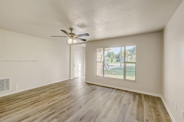 empty room with ceiling fan, light hardwood / wood-style flooring, and a textured ceiling