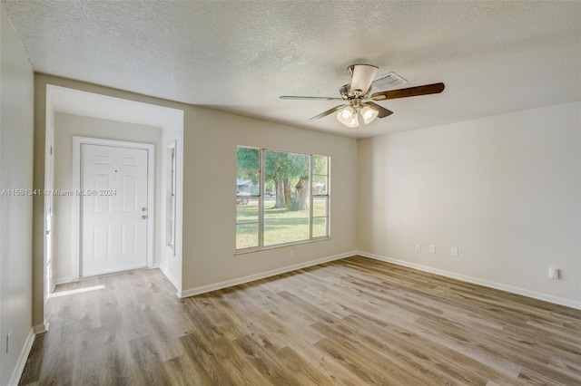 spare room featuring ceiling fan, light hardwood / wood-style flooring, and a textured ceiling