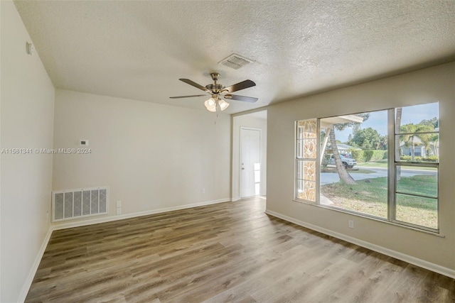 empty room with a textured ceiling, wood-type flooring, and ceiling fan