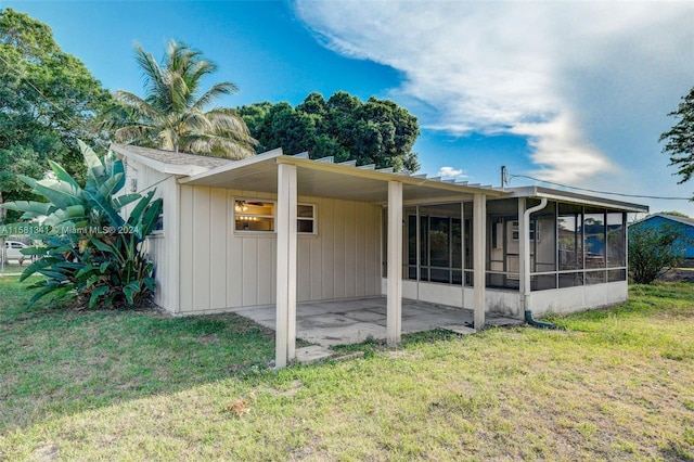 back of house featuring a sunroom and a lawn