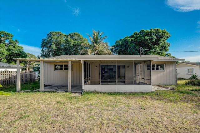 rear view of property featuring a sunroom and a lawn