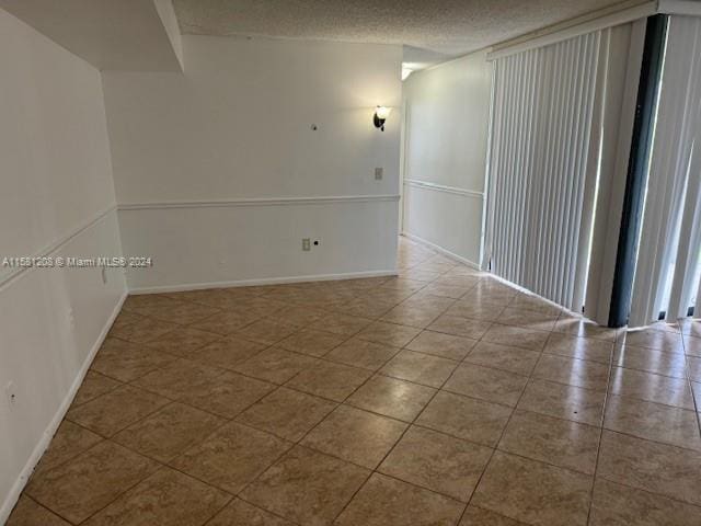 tiled spare room with a textured ceiling