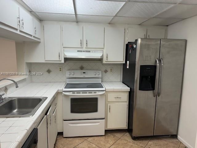 kitchen featuring tile countertops, sink, white electric stove, light tile patterned floors, and stainless steel fridge with ice dispenser