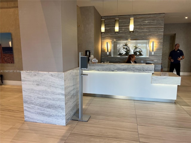 interior space with tile walls, light stone counters, hanging light fixtures, and light tile floors