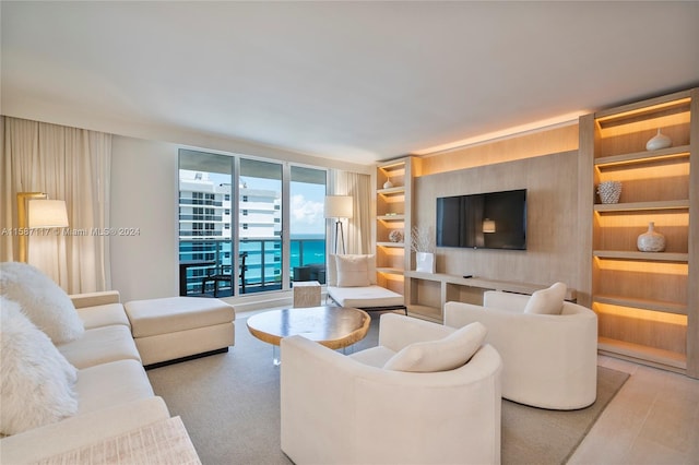 living room featuring floor to ceiling windows, built in shelves, and a water view