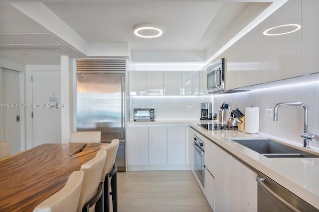 kitchen featuring sink, white cabinets, backsplash, and appliances with stainless steel finishes