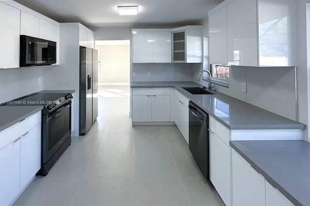 kitchen featuring electric range, dishwasher, sink, stainless steel fridge, and white cabinets