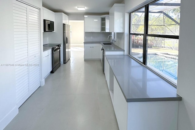 kitchen featuring tasteful backsplash, white cabinetry, sink, and stainless steel appliances