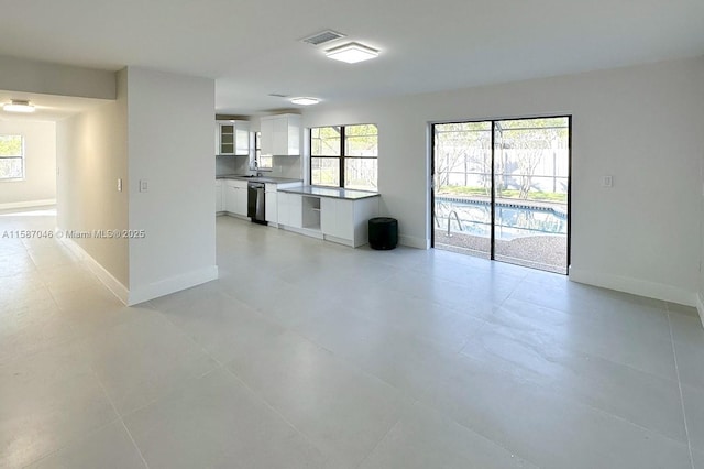 unfurnished living room with light tile patterned flooring and sink