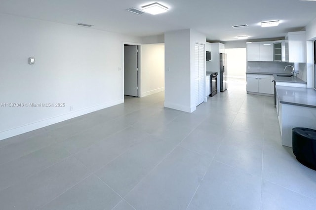 kitchen with white cabinets, sink, decorative backsplash, stainless steel fridge, and light tile patterned flooring