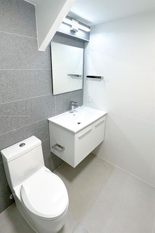 bathroom with tile patterned floors, vanity, toilet, and tile walls