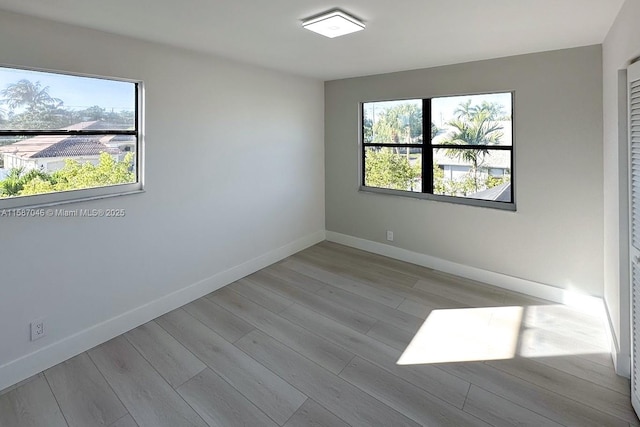 empty room featuring light wood-type flooring and a healthy amount of sunlight