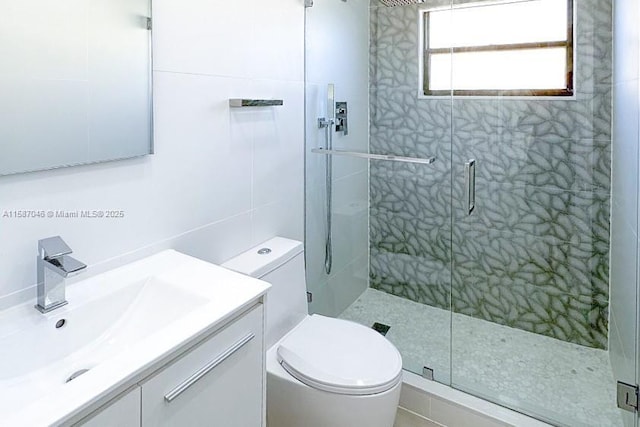 bathroom featuring an enclosed shower, vanity, toilet, and tile walls