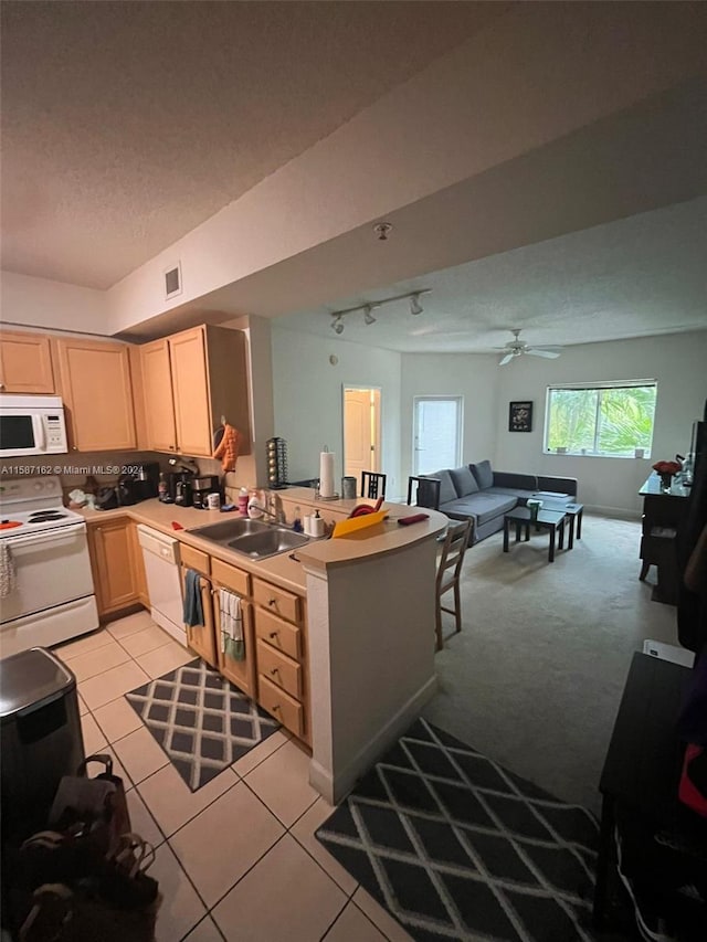 kitchen with kitchen peninsula, ceiling fan, light colored carpet, sink, and white appliances