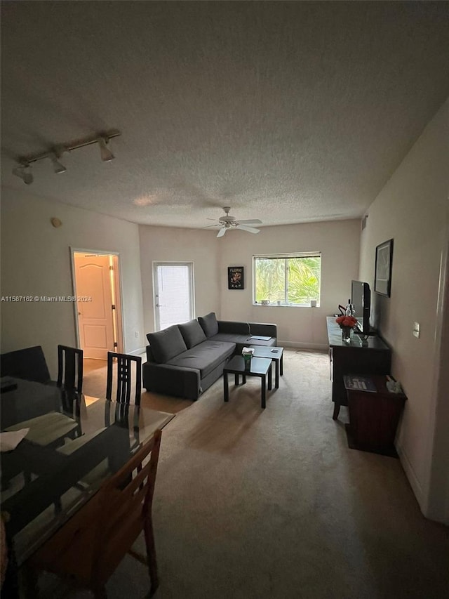 living room featuring ceiling fan, carpet floors, a textured ceiling, and rail lighting