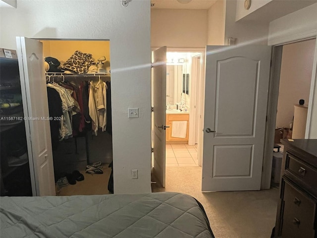 carpeted bedroom with ensuite bathroom, a walk in closet, and a closet