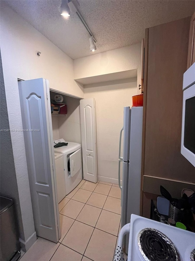 kitchen with white appliances, a textured ceiling, track lighting, and light tile flooring