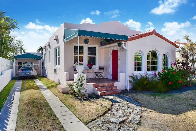 view of front of property featuring stucco siding, driveway, a porch, fence, and a tiled roof