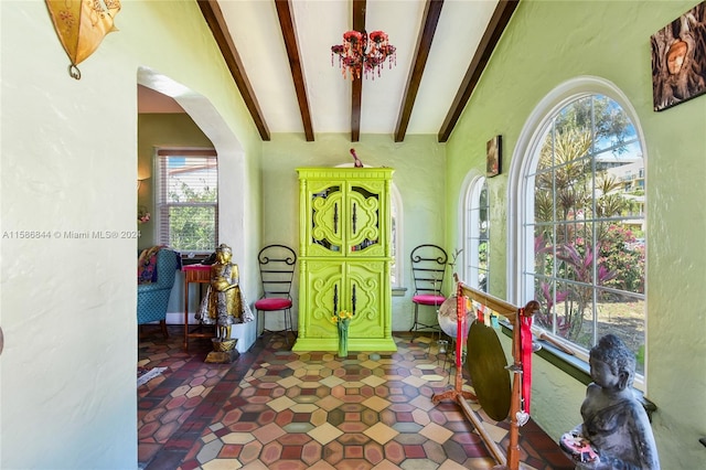 foyer entrance with beam ceiling, a notable chandelier, and dark tile flooring