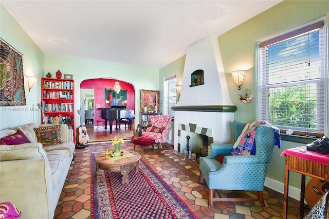 living area with a healthy amount of sunlight, baseboards, and arched walkways