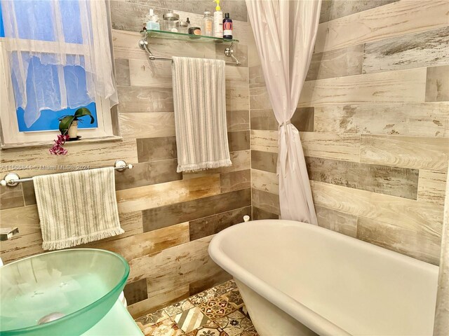 bathroom with a washtub and tile walls