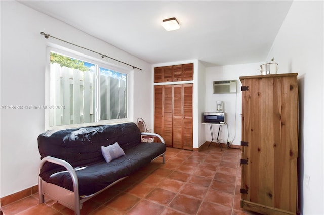 sitting room featuring tile patterned floors, baseboards, and a wall unit AC