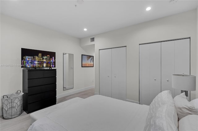 bedroom with two closets and light hardwood / wood-style floors