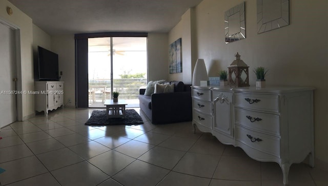 living area with expansive windows, light tile patterned flooring, and ceiling fan