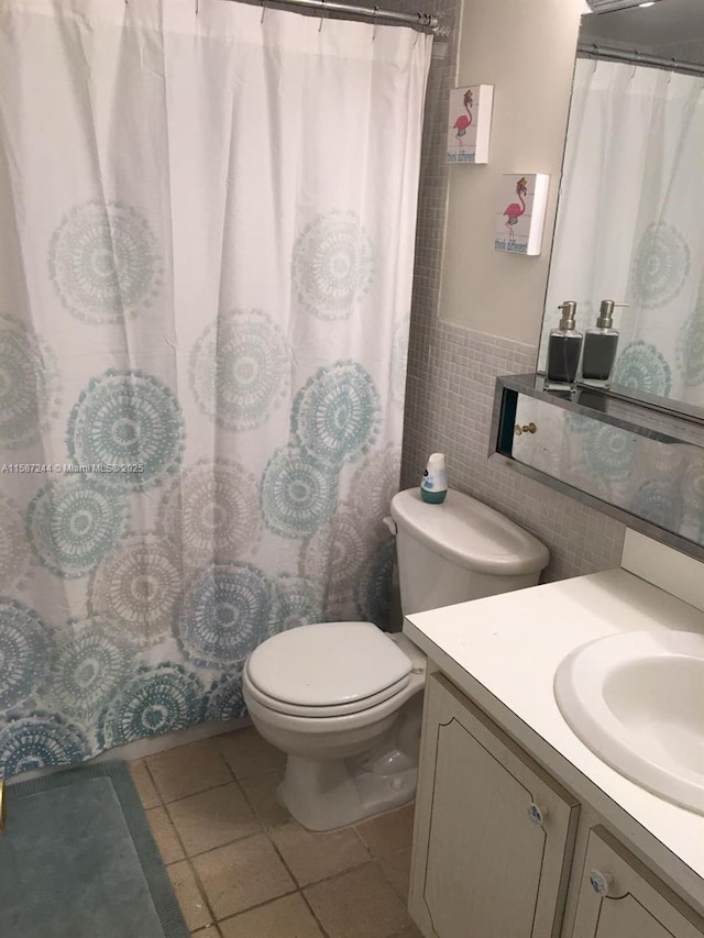 bathroom with tile patterned flooring, vanity, tile walls, and toilet