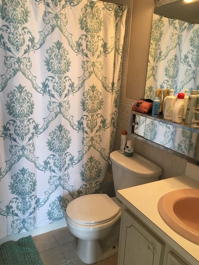 bathroom featuring vanity, backsplash, tile patterned flooring, toilet, and tile walls