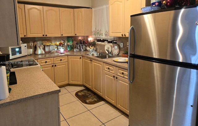 kitchen with light tile patterned flooring, stainless steel refrigerator, sink, decorative backsplash, and range