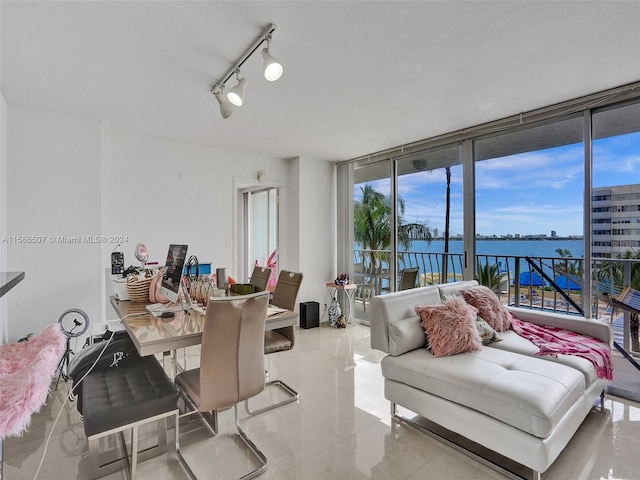 dining area with light tile flooring, track lighting, and a water view