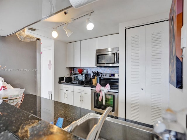 kitchen featuring stainless steel appliances, white cabinets, tasteful backsplash, and rail lighting