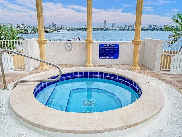 view of swimming pool featuring a water view and a hot tub