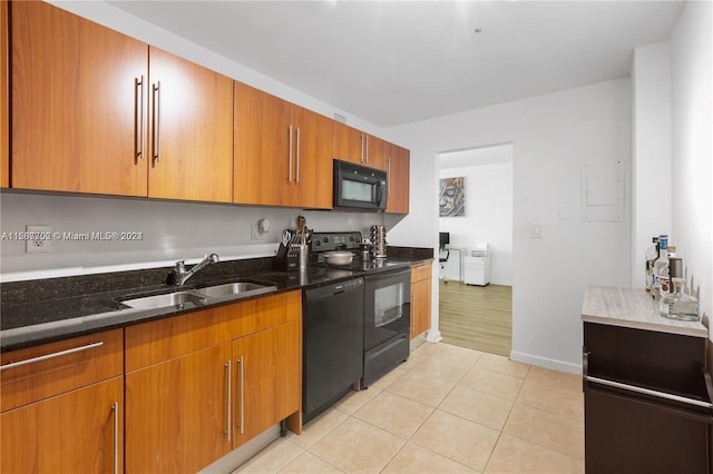 kitchen with dark stone counters, sink, light hardwood / wood-style flooring, and black appliances