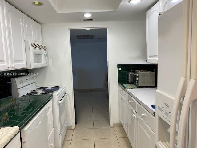 kitchen featuring white appliances, white cabinets, tile countertops, tasteful backsplash, and light tile flooring