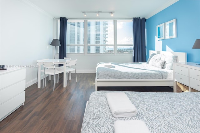 bedroom featuring crown molding, track lighting, and dark hardwood / wood-style flooring