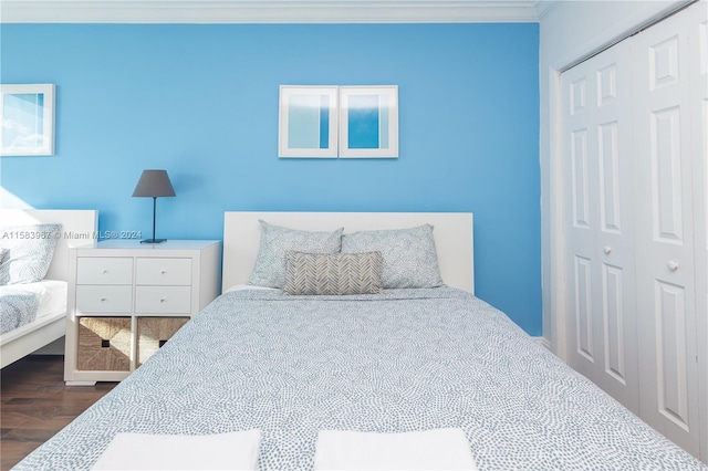 bedroom featuring dark hardwood / wood-style floors, ornamental molding, and a closet