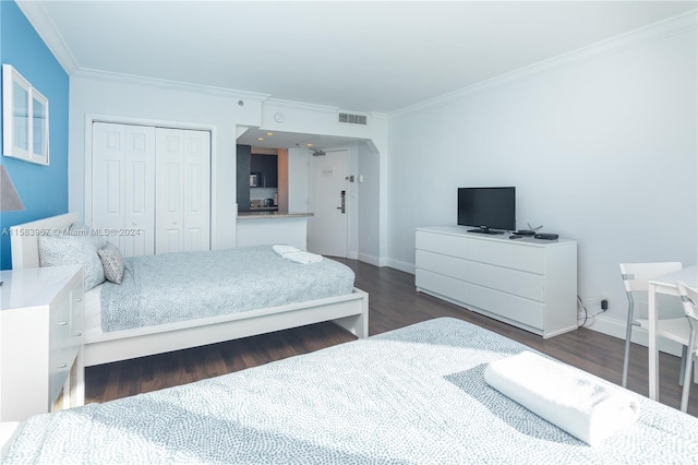 bedroom with dark hardwood / wood-style floors, ornamental molding, and a closet