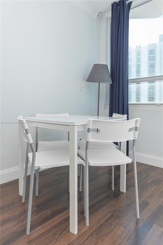 dining space with ornamental molding and dark wood-type flooring