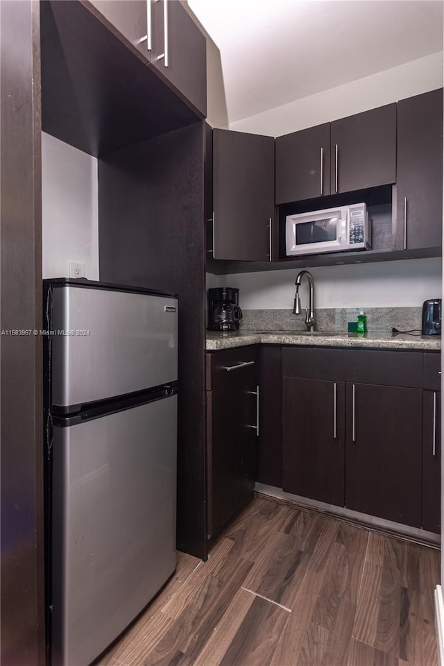 kitchen with sink, stainless steel fridge, dark brown cabinets, and dark hardwood / wood-style flooring