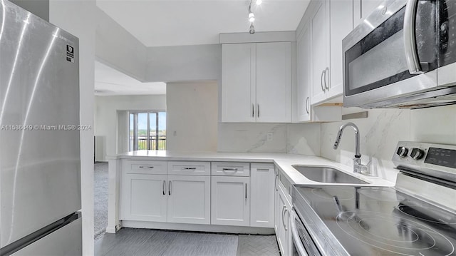 kitchen featuring sink, kitchen peninsula, white cabinetry, and appliances with stainless steel finishes