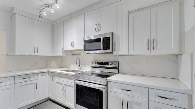 kitchen with sink, range with electric stovetop, backsplash, and white cabinetry