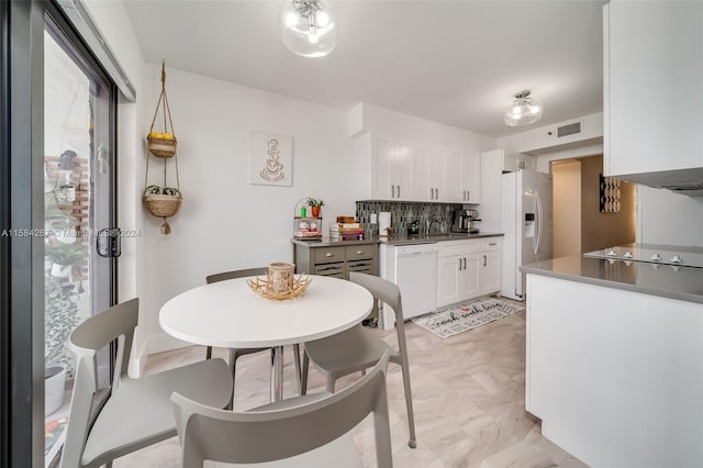 kitchen featuring black electric stovetop, refrigerator with ice dispenser, backsplash, white dishwasher, and white cabinets