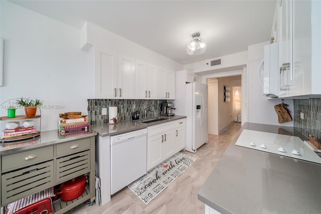 kitchen with sink, white appliances, white cabinetry, and backsplash