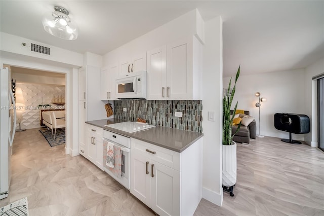 kitchen with tasteful backsplash, white appliances, and white cabinetry