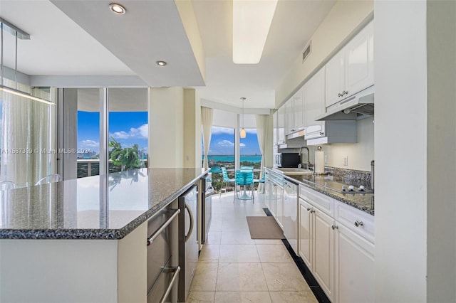 kitchen with dark stone countertops, plenty of natural light, white cabinetry, and light tile floors